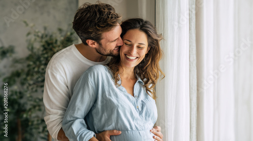 Couple shares a loving moment together as they prepare for the arrival of their baby at home near a window during daylight