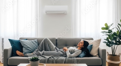 Woman Relaxing on Sofa Under Air Conditioner in Modern Living Room.