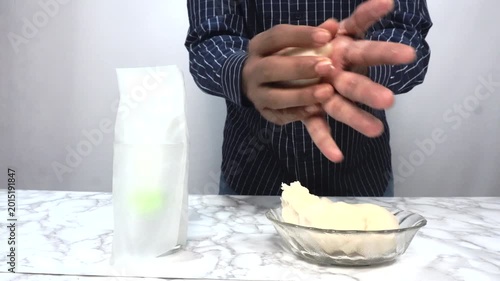 Man Rolling Dough by Hand in Kitchen for Homemade Bread or Pizza Preparation, Close-up of a man shaping and rolling soft dough by hand on a kitchen counter during homemade bread or pizza preparation. 