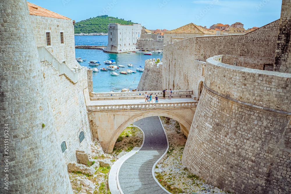 Dubrovnik, Croatia: Stone bridge and fortress walls overlooking harbor with boats