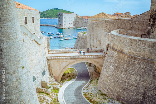 Принти на полотні Dubrovnik, Croatia: Stone bridge and fortress walls overlooking harbor with boat