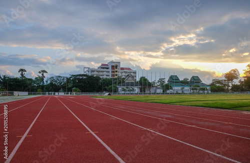 Athletic Track and Skyline View: The vibrant red of an athletic track leads the eye towards a building under a serene sky, capturing a moment of focus and anticipation.