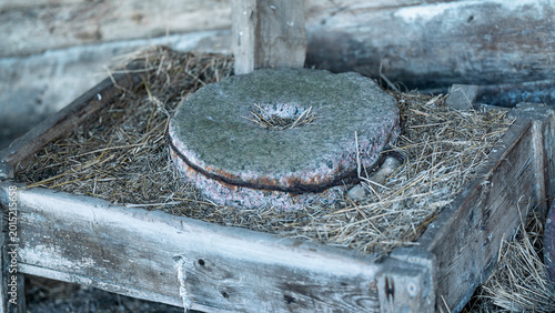 Canvas-taulu Old grindstone sitting on straw within a rustic wooden feeder, illustrating trad