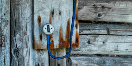 Photos Rustic electrical switch on a weathered wooden board, with a blue cable running