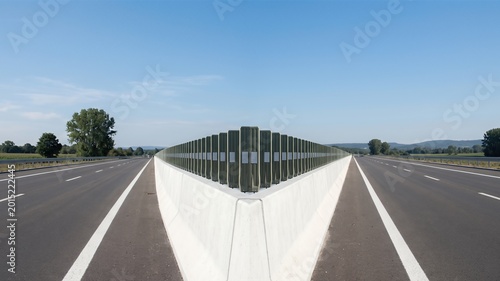 Symmetrical Highway Landscape with Reflective Barrier and Clear Blue Sky