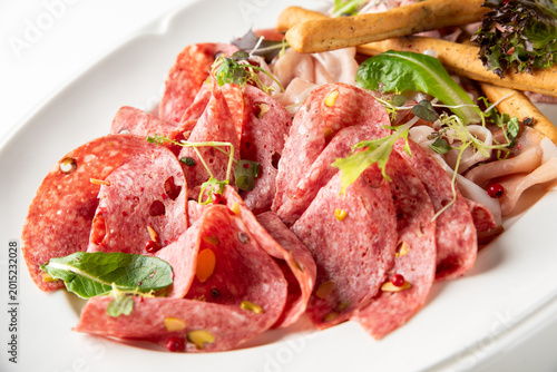 Foto Sliced cured meat platter featuring thin folds of salami with pistachios and pep