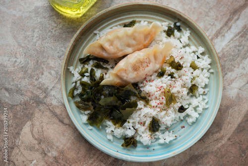 Foto Turquoise plate with japanese wakame gohan and steamed dumplings, horizontal sho