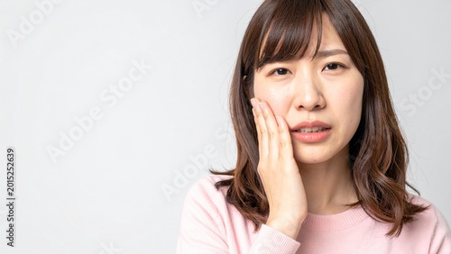頬を押さえて歯痛に悩む若い日本人女性 AI生成素材