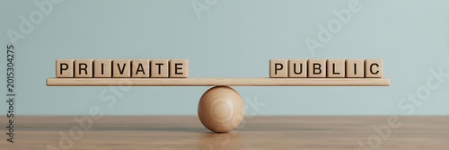 A wooden seesaw with blocks spelling private and public in balance on a table
