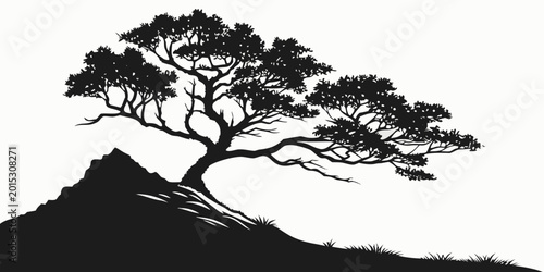 Slika na platnu Silhouette of a windswept tree on a grassy incline with a rocky peak black and w