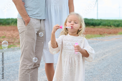 Bild auf Leinwand Family moment captured outdoors with a child blowing bubbles on a path