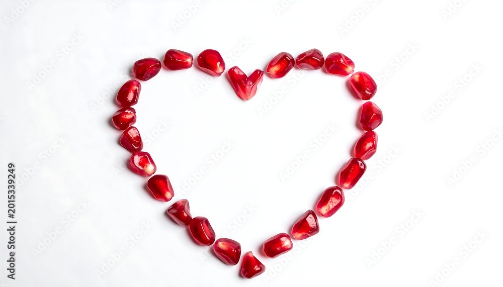 Obraz premium Heart shape formed from vibrant red pomegranate seeds against a clean white backdrop, symbolizing love and affection
