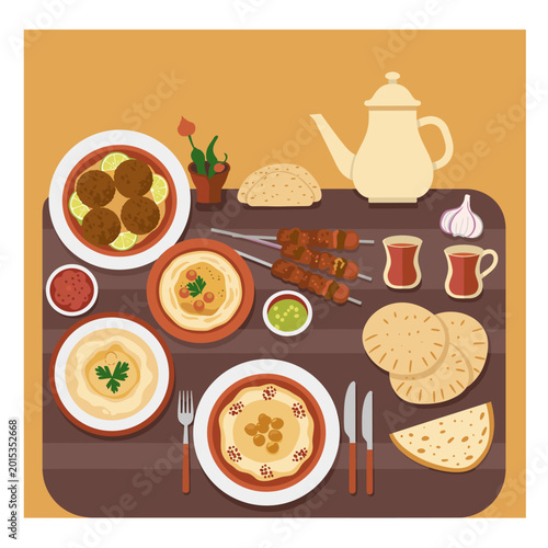 A spread of Middle Eastern cuisine featuring falafel, hummus, kebabs, pita bread, and tea, set on a table.