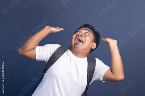 Young student with a backpack looks up with a scared and fearful expression at something above him.