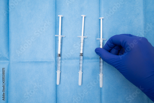 Fotografia Hand in gloves preparing medical syringes for injection