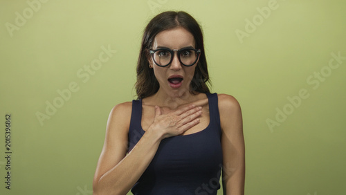 Foto Young hispanic woman with hand on chest and open mouth expression against olive green studio background; surprise