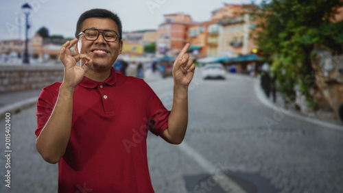 Photography Hispanic man wearing glasses and red polo making ok sign with hand and pointing finger on street; confidence optimism joy