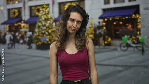 Fotografija Woman points finger gun to side of head on street with festive building facades and parked bicycles; despair