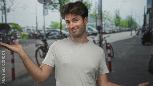 Obraz na płótnie Man shrugging with palms up on street showing bare hands and forearms in a casual tshirt; uncertainty doubt hesitation