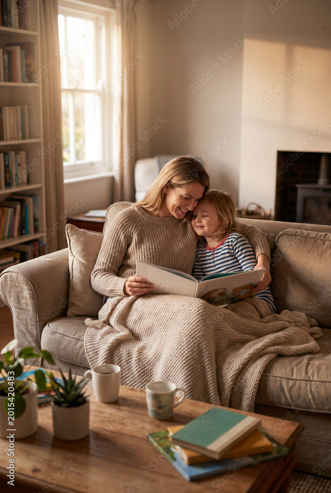 Obraz premium Woman on sofa using smartphone in sunny home living room