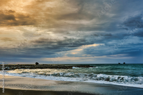 Beach waves crashing on rocky shore at sunset