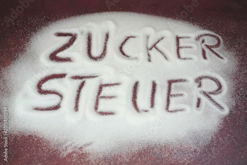 Verteilter Zucker mit Inschrift Zuckersteuer die demnächst auch in Deutschland eingeführt werden soll