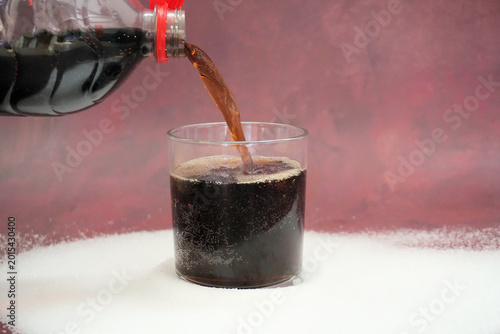 Ein Glas mit Cola und verteiltem Zucker 