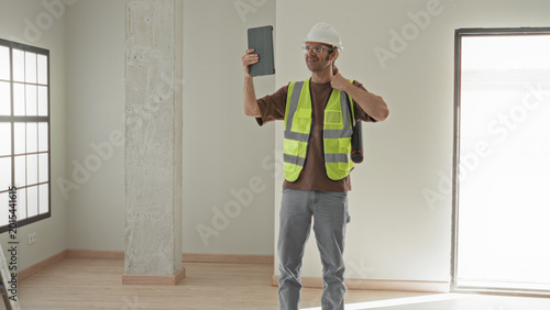 Fotografía Man architect holds tablet aloft with one hand and hand on hip in building; site inspection confidence