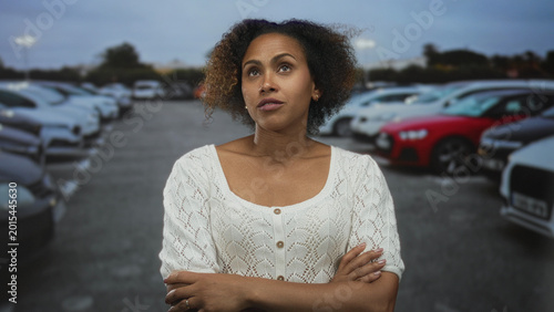 Quadro su tela Woman with arms crossed in a street parking lot, eyes narrowed and pursed lips in a dismissive pose; skepticism