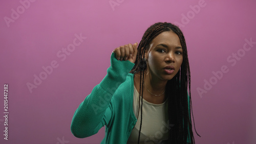 Fotografía Woman with raised hands and long braids making a shrugging gesture in pink studio; confusion questioning doubt