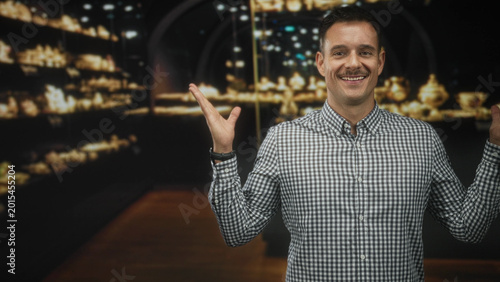 Cuadro en lienzo Man raising hands palms out in studio beside lit display shelf, checkered shirt and moustache visible; friendly charm