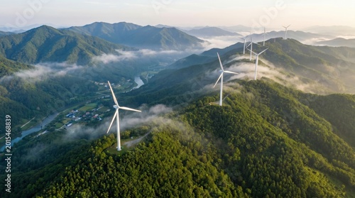 Wind turbines generating clean energy in misty mountain forest at sunrise