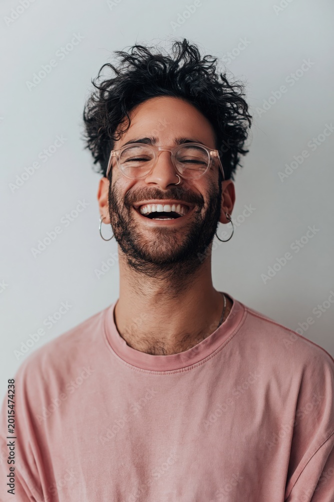 Fototapeta premium Young man laughing with eyes closed in studio setting