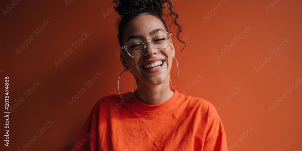 Obraz premium Young woman laughing and smiling against orange backdrop