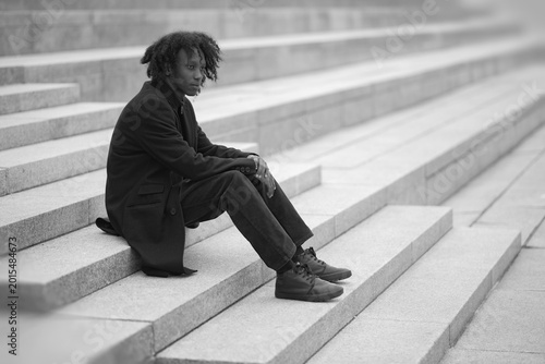 Solitary Young Man Sitting on Endless Stone Stairs in Monochrome Perspective with Copy Space