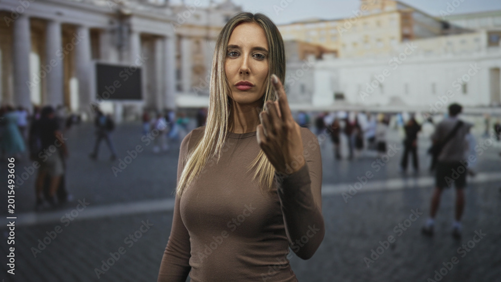 Fototapeta premium Woman points finger to camera showing hand and face in a busy building square at the vatican; confidence pilgrimage.