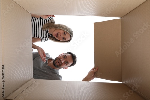 Schilderij op canvas Couple looking into cardboard box on white background, view from inside package