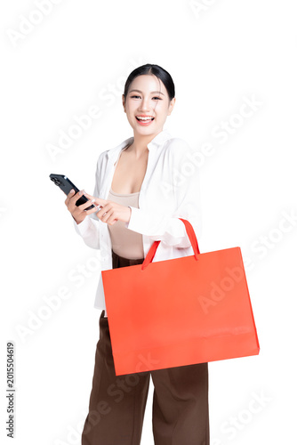 Happy young Asian woman holding shopping bags and using application for choosing product on your mobile phone with enjoyment with shopping online concept. on transparent background.