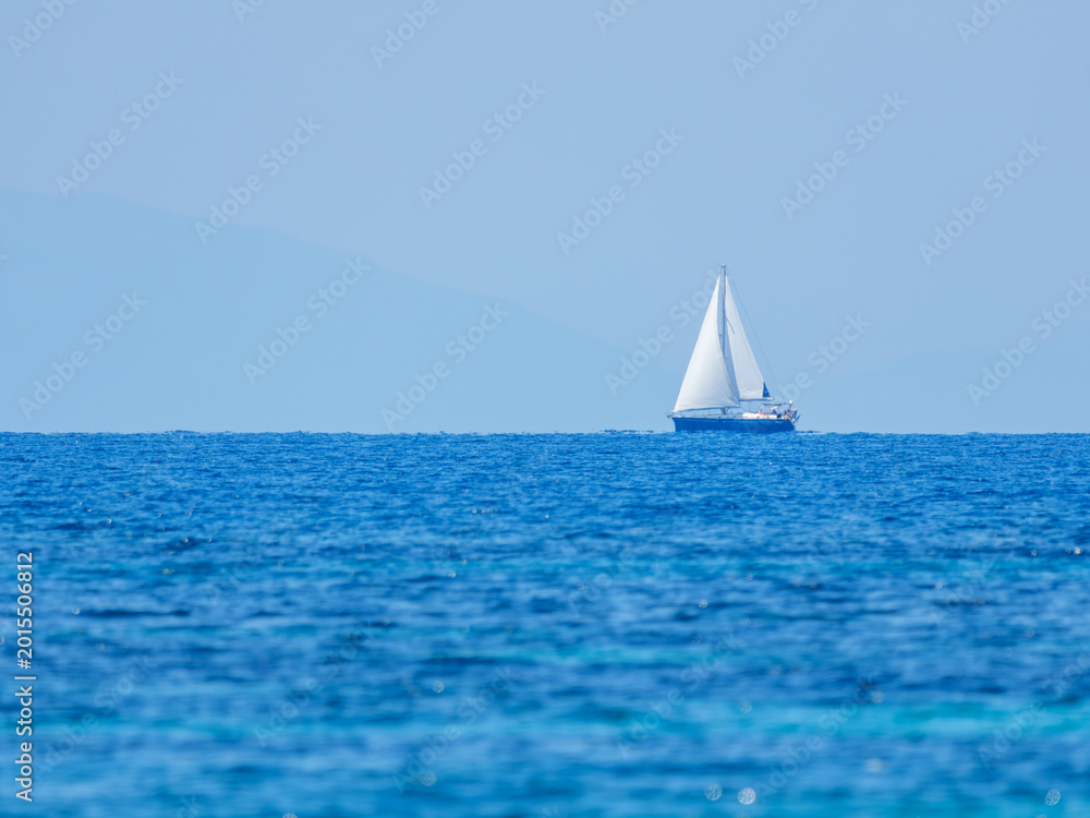 Fototapeta premium White Sailboat Sailing on Blue Sea Under Clear Sky