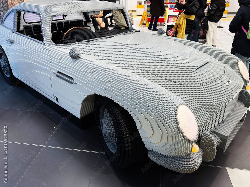 Naklejka premium Life size LEGO car sculpture of an Aston Martin displayed in a busy toy store in London, UK with shoppers taking photos and admiring the detailed brick model