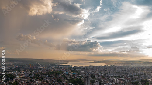 Stunning sunset over a coastal city with dramatic storm clouds.