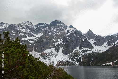 Fotografie Snow-capped mountains rise dramatically above a tranquil lake surrounded by lush