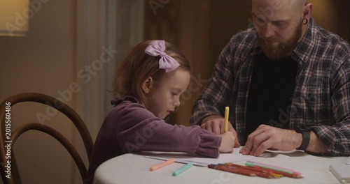 A father guides his daughter as they draw together, sharing joy and imagination in a warm, inviting room