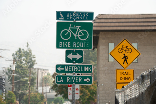 Foto Street signs indicate bike route, Metrolink, and La River path directions