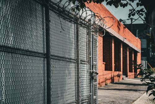Фотография Chain link fence with razor wire and locked gate in front of brick building