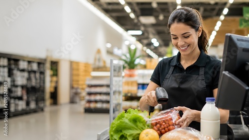 A supermarket cashier scanning groceries and smiling