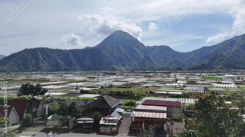 Vast Agricultural Fields and Rural Village Nestled in a Scenic Valley with Majestic Green Mountains