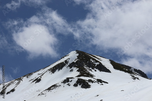 Valokuva A snow-covered mountain landscape where climbers appear tiny