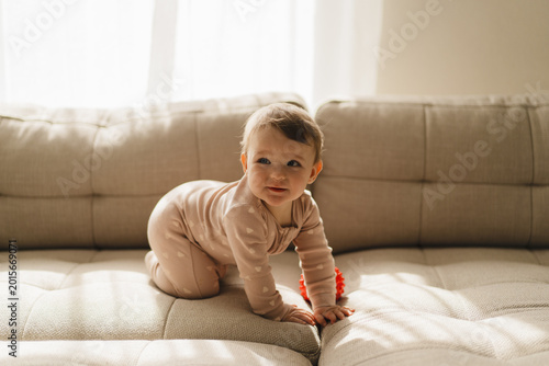 A young child plays with an educational toy. The sun is shining through a window, creating a warm atmosphere. Concept of teething period, baby care, early development, and healthy childhood life