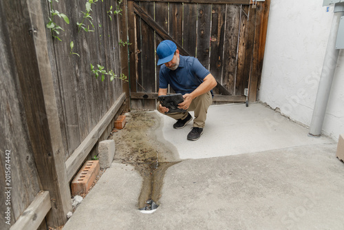 Fotografie A home inspector checks and takes a pictures of a drainage on the side of a resi